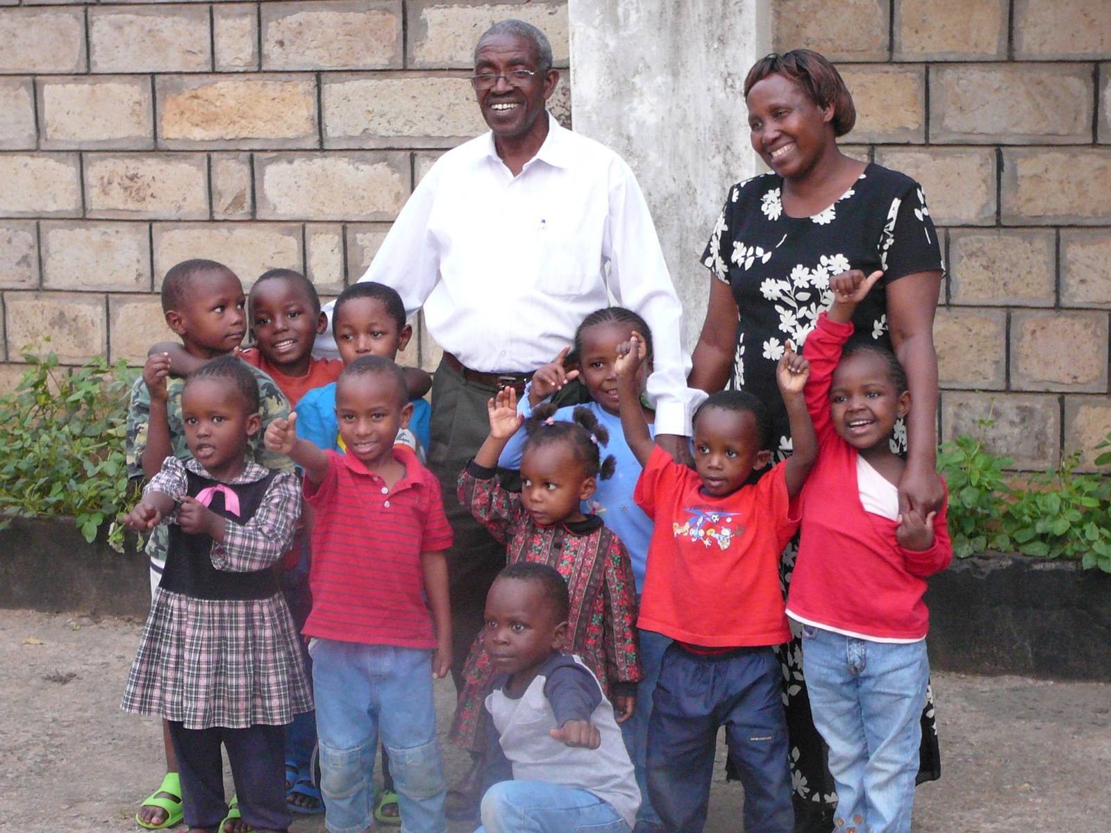 Pastor and Mama Karau surrounded by smiling children in Mathare Valley, Kenya
