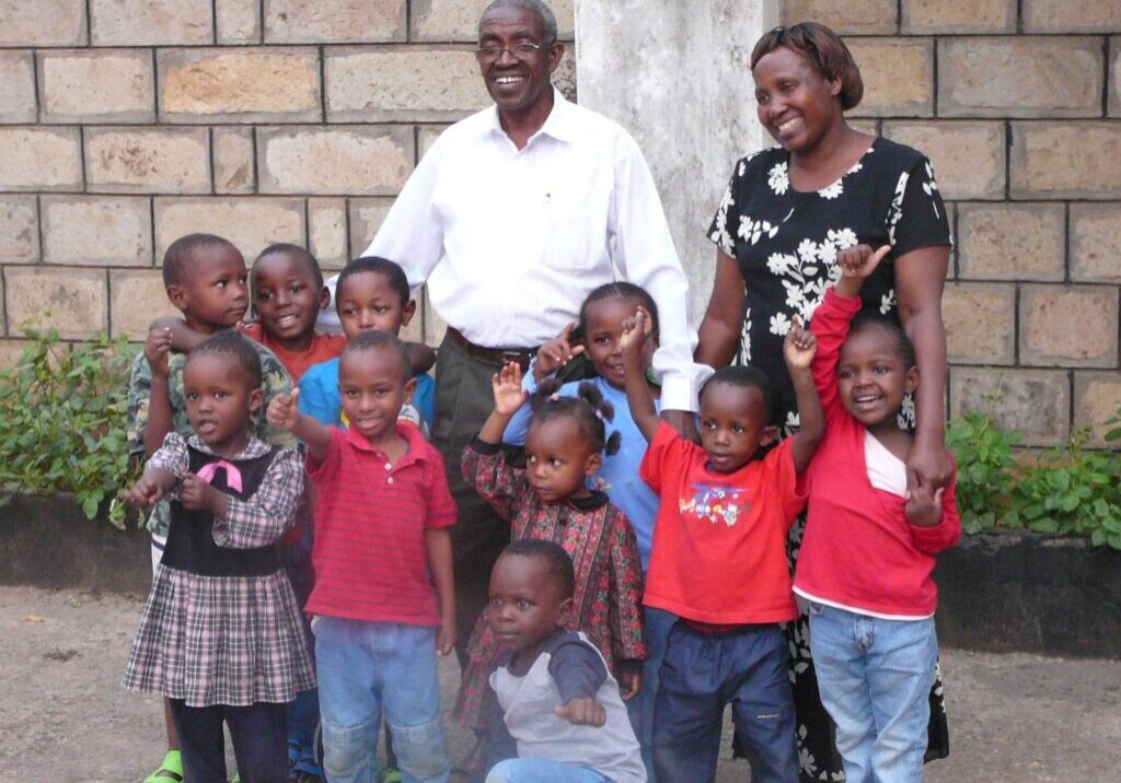 Pastor and Mama Karau surrounded by smiling children in Mathare Valley, Kenya